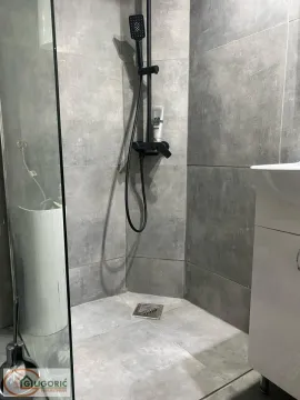 Modernly equipped bathroom with a walk-in shower and grey ceramic tiles. - image 5