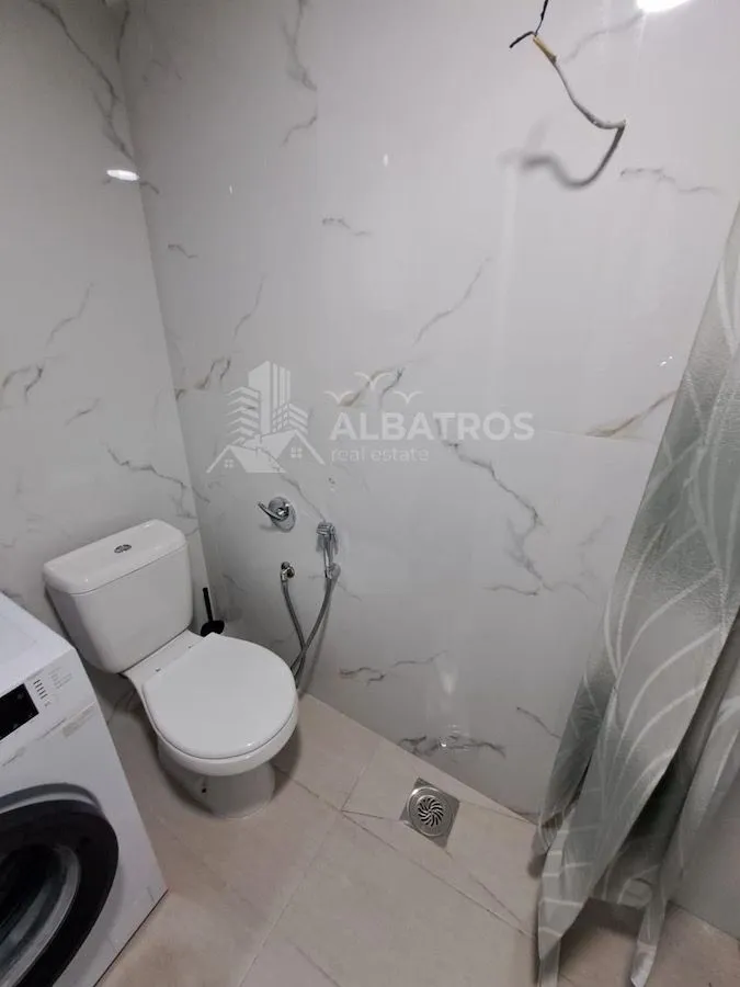 Manje kupatilo sa wc šoljom i veš mašinom.