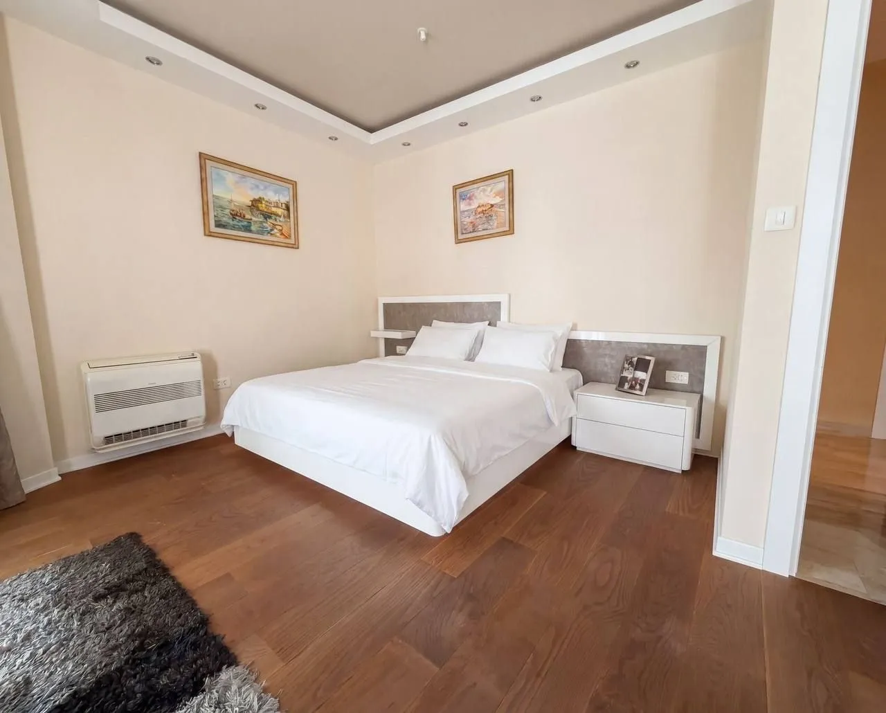 A furnished bedroom with a double bed and wooden flooring.