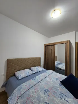 A simply furnished bedroom with a double bed and a wooden wardrobe. - image 4