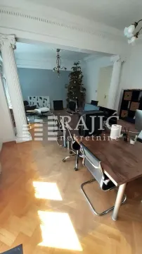 Spacious living room with office desks and decorative columns. - image 8