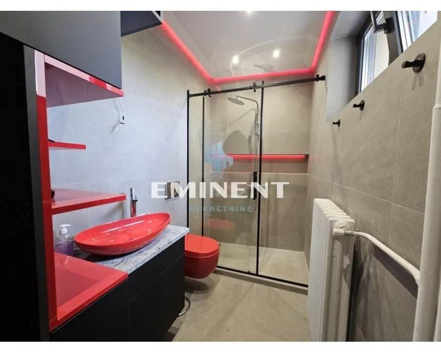 Modern bathroom with a shower cabin and red details.