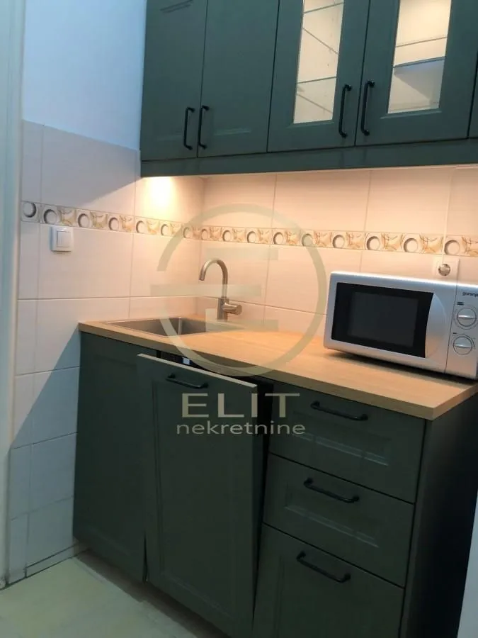 Small kitchen with dark green cabinets, sink, and a microwave.