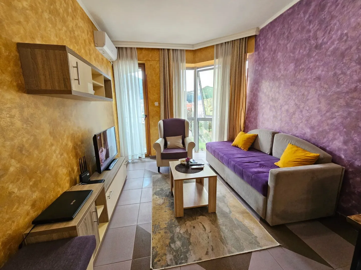 Living room with a sofa, armchair, TV, and access to the terrace.