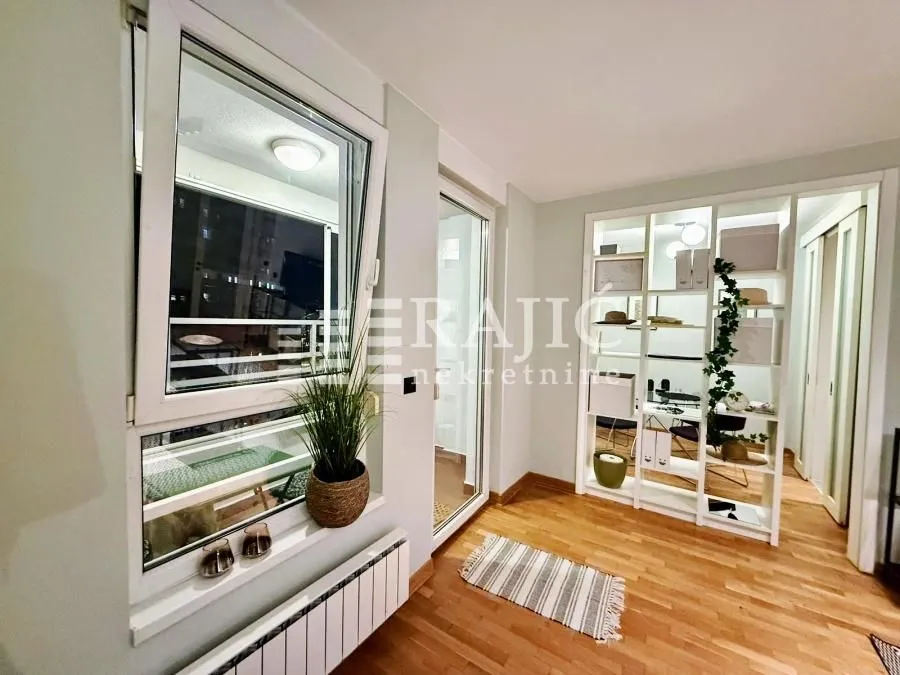 Bright living room with wooden flooring, windows, and access to the terrace.