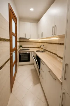 Moderna i svijetla kuhinja sa bijelim elementima i drvenom radnom pločom. - image 5