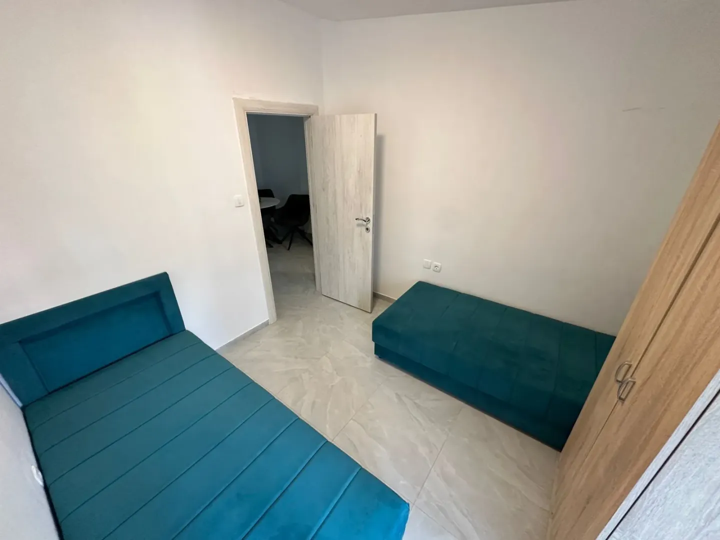 Manja spavaća soba sa dva plava kreveta i garderoberom.