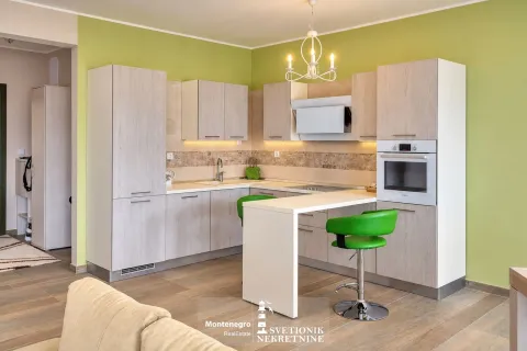 Moderna kuhinja sa šankom i zelenim stolicama povezana sa dnevnim boravkom. - image 7