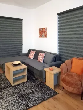 Living room with a grey sectional sofa, armchair, and wooden coffee tables. - image 8