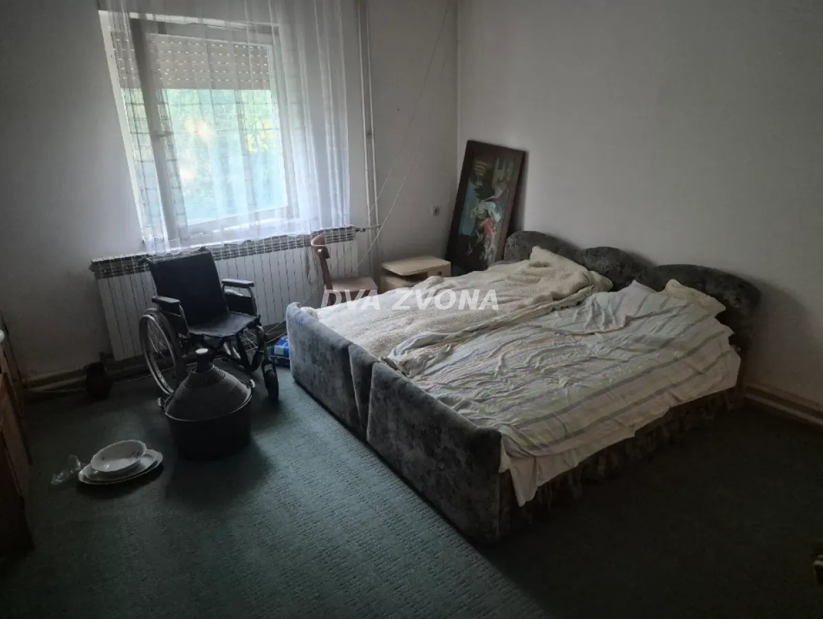 Spavaća soba sa krevetom, prozorom i invalidskim kolicima.