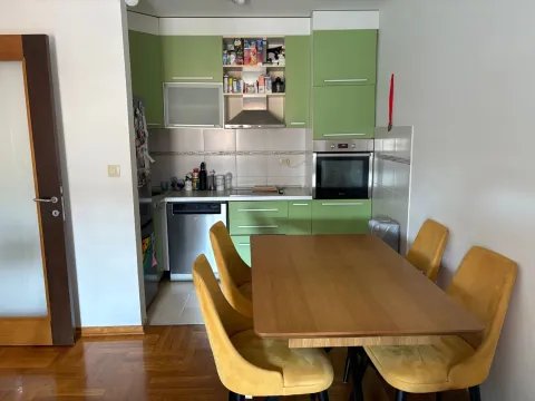 Kuhinja sa zelenim elementima i trpezarijskim stolom sa žutim stolicama. - image 2