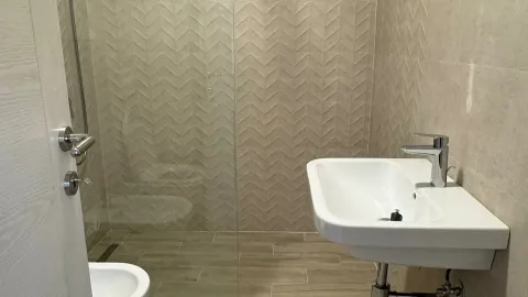 Pogled na moderno opremljeno kupatilo sa tuš kabinom i umivaonikom. - image 4