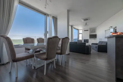 Spacious living room with a dining area and large windows with a view. - image 2