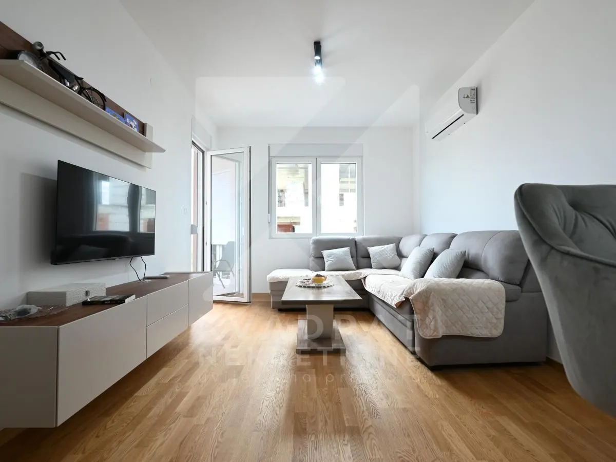 Living room with a corner sofa, TV, and access to the terrace.