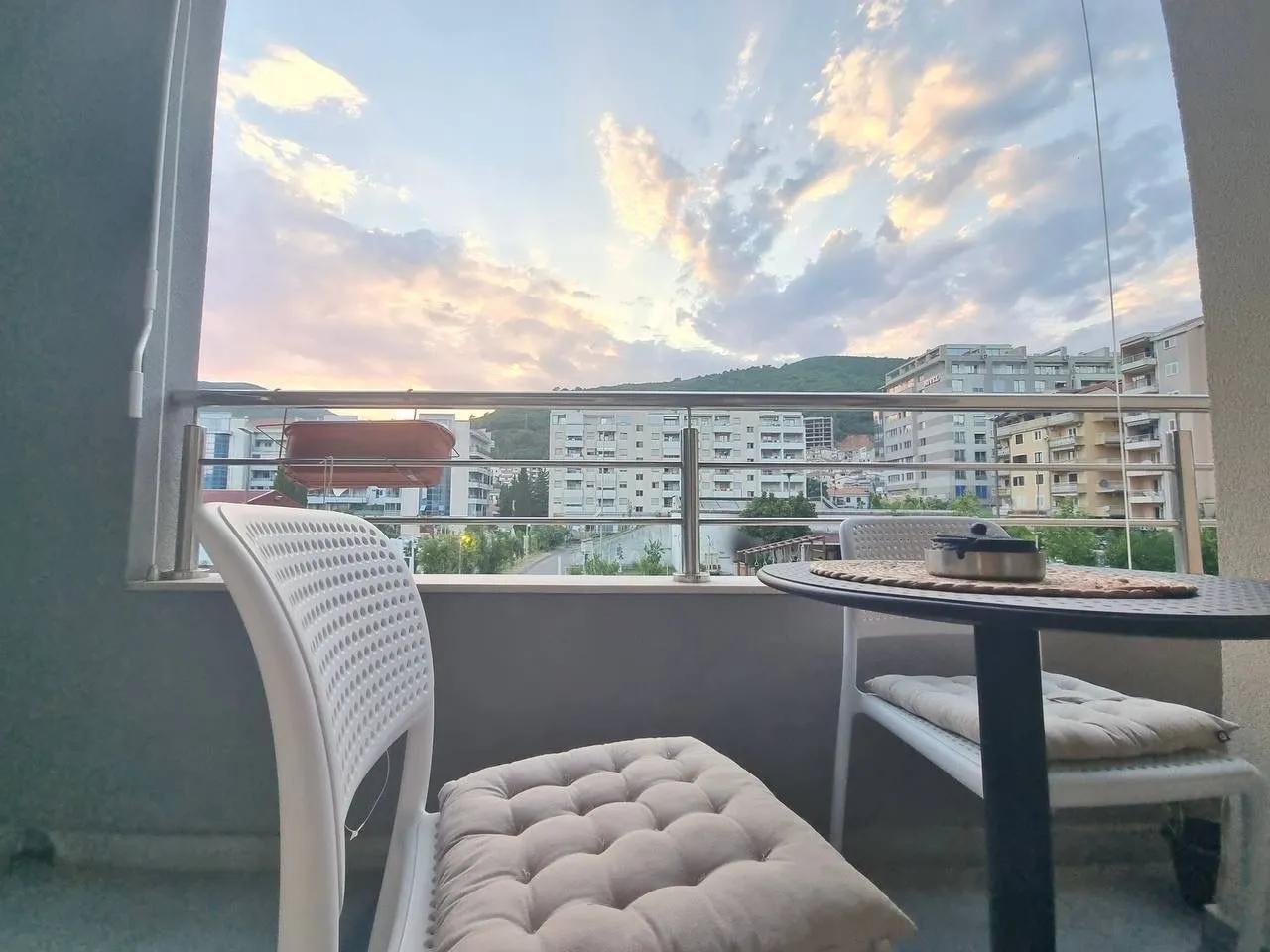 Namještena terasa sa stolom, stolicama i pogledom na grad.