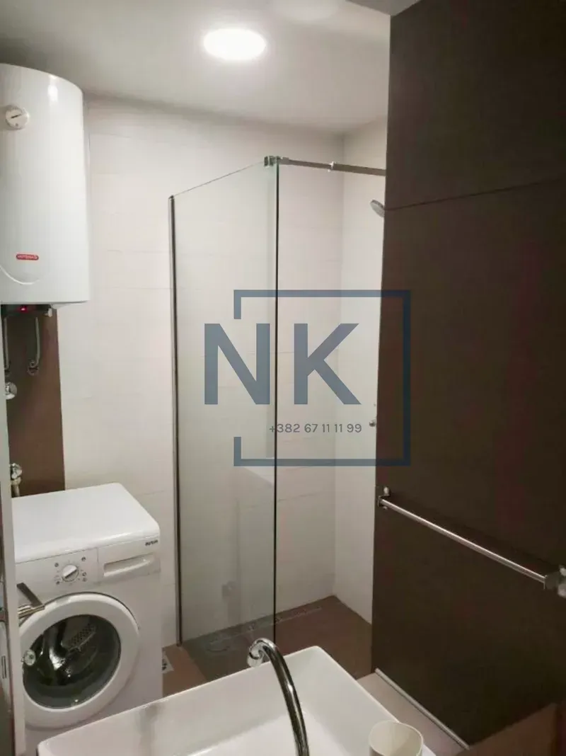 Bathroom equipped with a shower cabin, washbasin, washing machine and water heater.