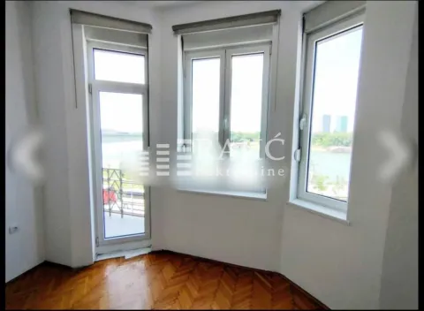 Empty room with parquet flooring and large windows offering a river view. - image 3