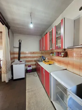 Starija kuhinja sa crvenim elementima i peći na drva. - image 2