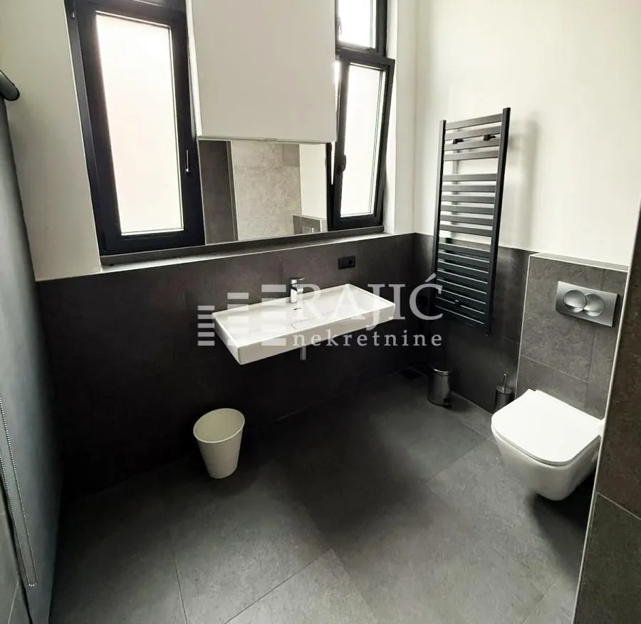 Modern bathroom with a washbasin, wall-hung toilet, and window.