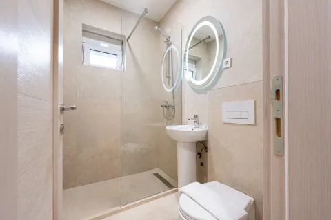 Modern bathroom with a walk-in shower, washbasin, and illuminated mirror. - image 9