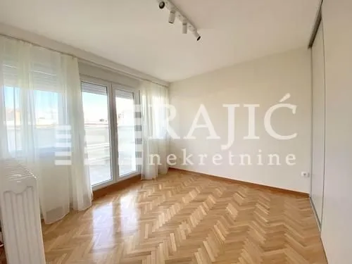 Empty room with parquet flooring and balcony doors.