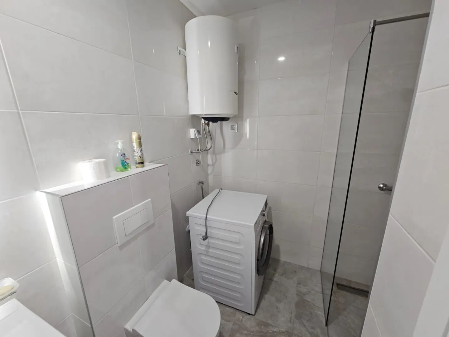 Moderne kupatilo sa tuš kabinom, WC šoljom, veš mašinom i bojlerom.