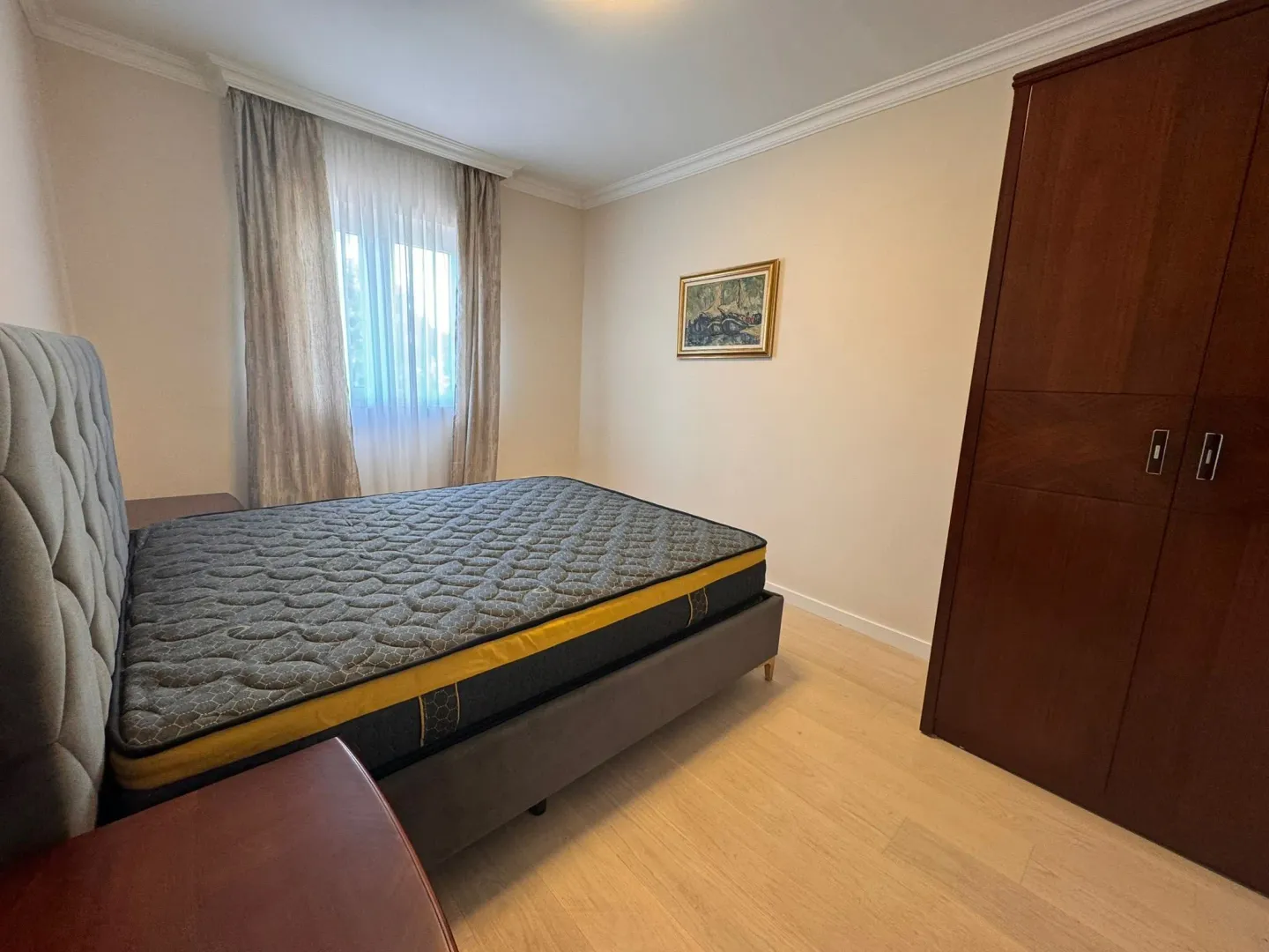 Bedroom with a double bed, wooden wardrobe and a window.