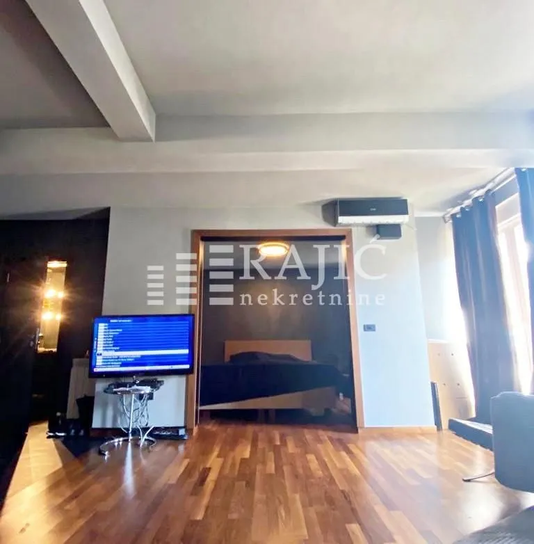 Living room with hardwood flooring and a view into the bedroom.