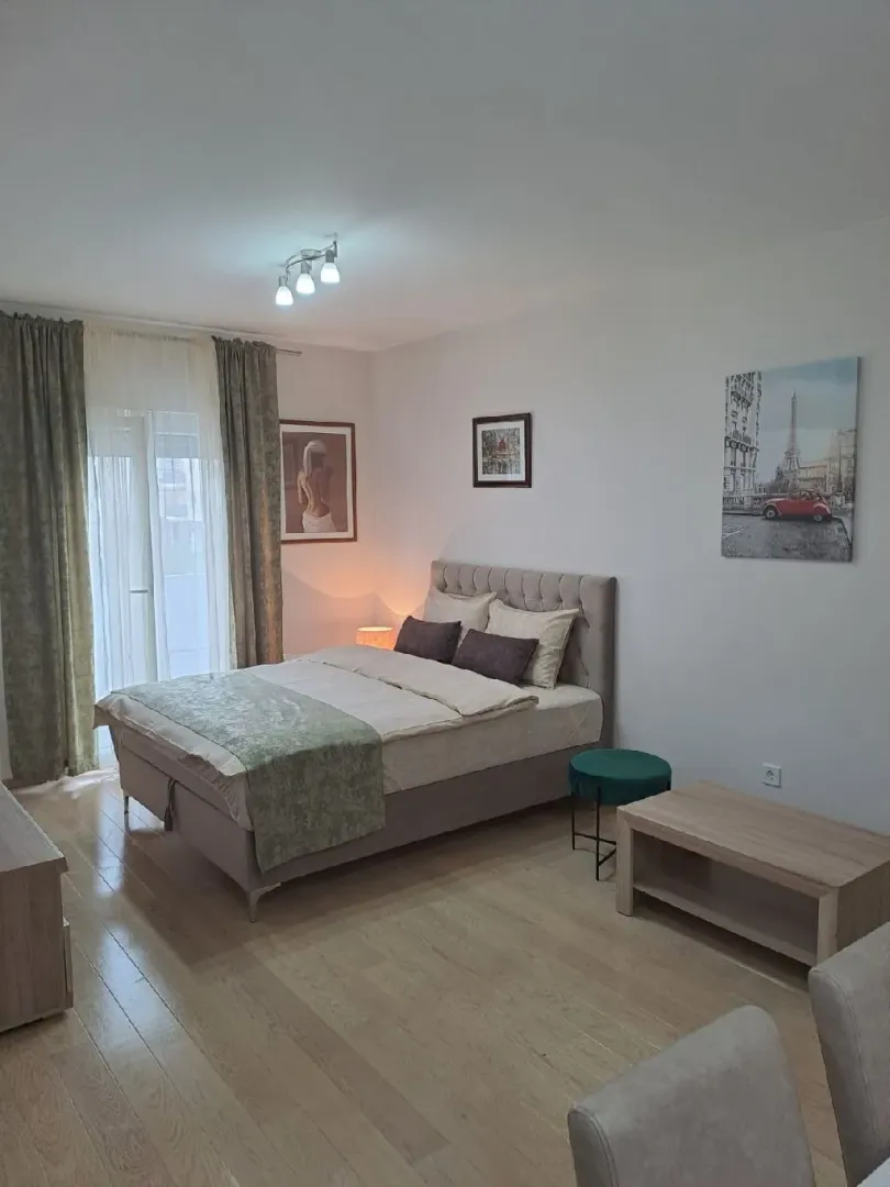 A furnished bedroom with a double bed and a window with curtains.