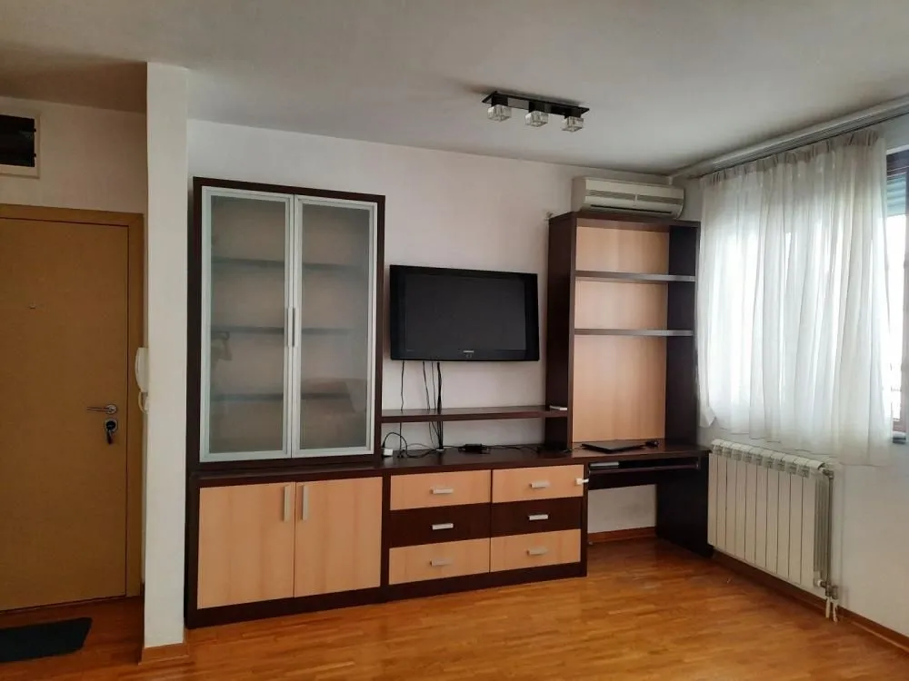 Living room with wooden furniture, TV, and laminate flooring.