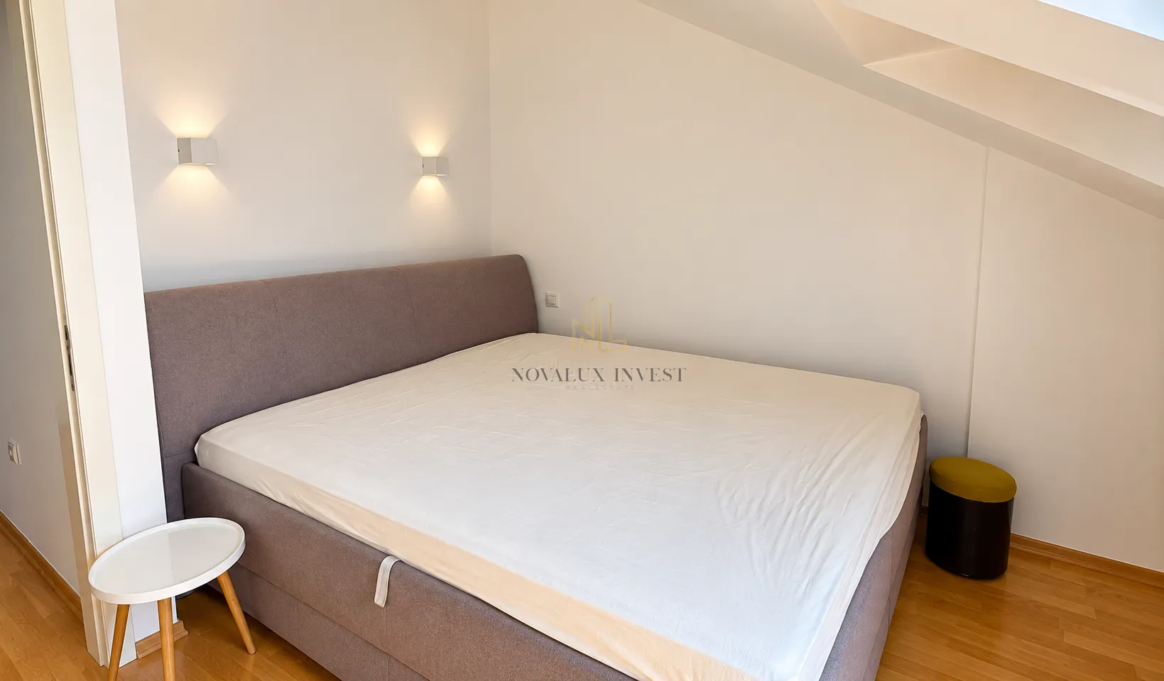 Bedroom with a large double bed and a small bedside table under sloped ceilings.