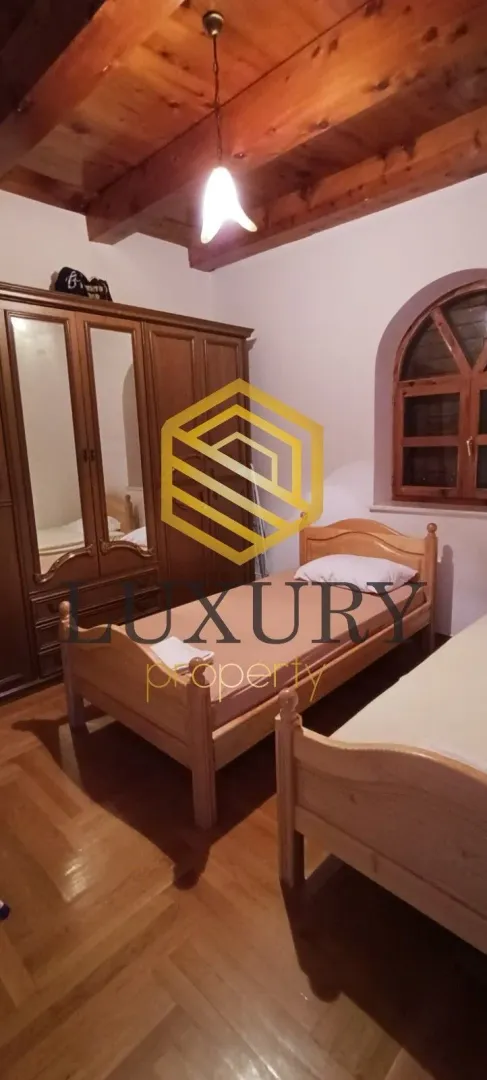 Bedroom with wooden furniture and a ceiling beam.