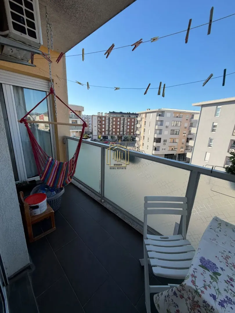 Namješten balkon sa stolom, stolicama i visećom ležaljkom.