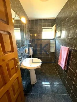 Bathroom tiled in dark tiles with a washbasin and mirror. - image 11