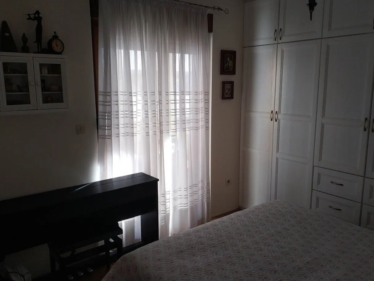 Spavaća soba sa velikim bijelim ormarom i prozorom sa zavjesama.