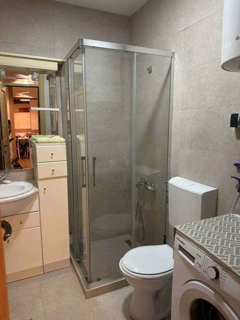 Bathroom with a shower cabin, washbasin, and washing machine.