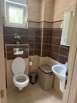 Manje kupatilo sa WC šoljom, umivaonikom i pločicama u braon tonovima. - image 9