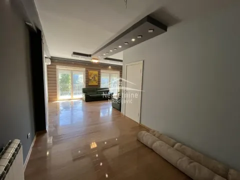 Spacious living room with glossy flooring and a dropped ceiling with lighting. - image 2
