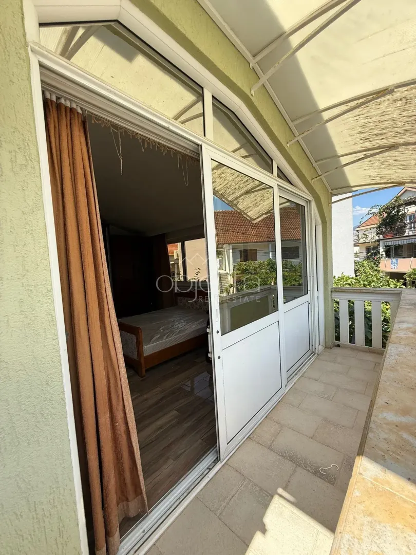 Natkriveni balkon sa izlazom iz sobe i pogledom na okolinu.