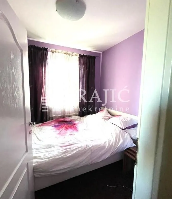 Small bedroom with a double bed and purple walls.