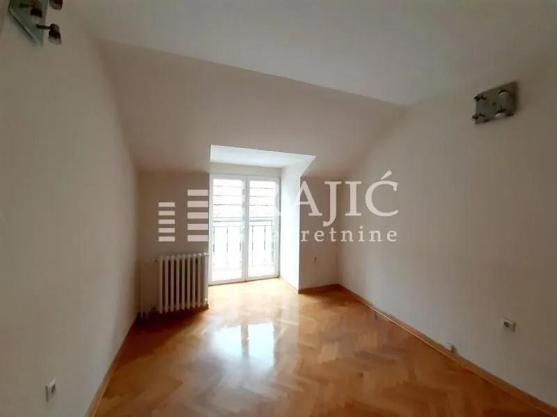 Empty room with parquet flooring and balcony doors.