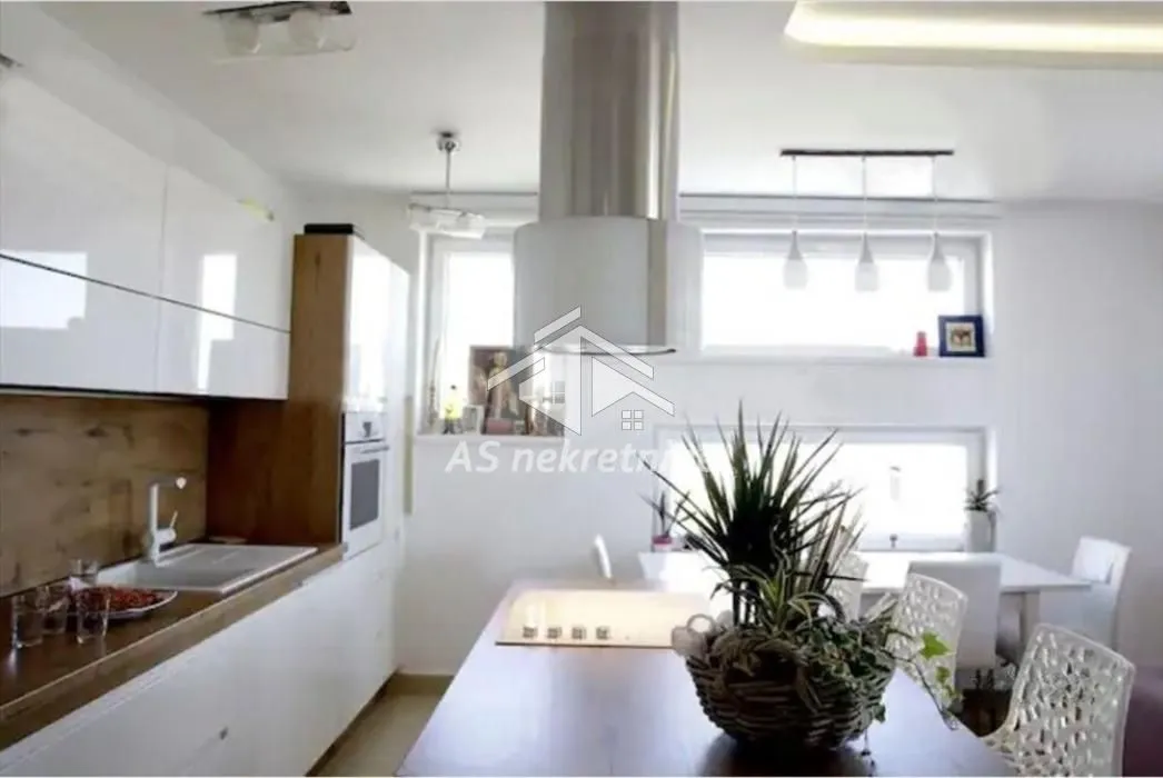 Modern kitchen with white units and a dining table.