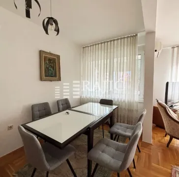 Dining area with a table and grey chairs in the living room. - image 4