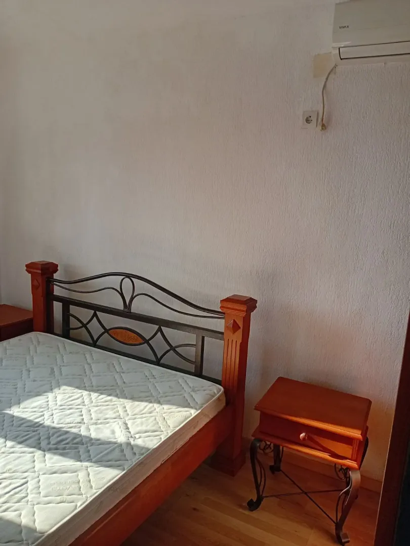 Spavaća soba sa bračnim krevetom i noćnim stočićem.