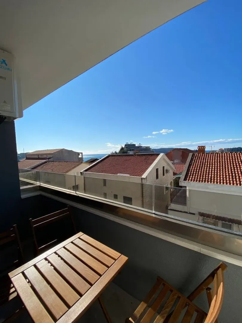 Furnished balcony with a table and a view of the sea and town.