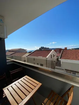 Furnished balcony with a table and a view of the sea and town. - image 2