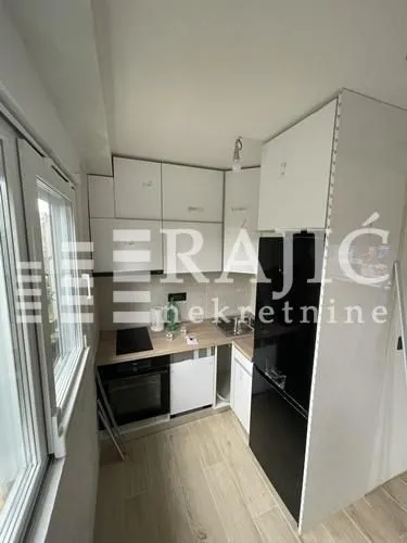 Compact equipped kitchen with white cabinets and built-in appliances.