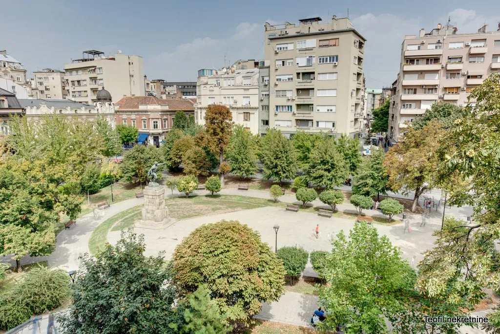 Pogled sa prozora na park i okolne zgrade u gradu.