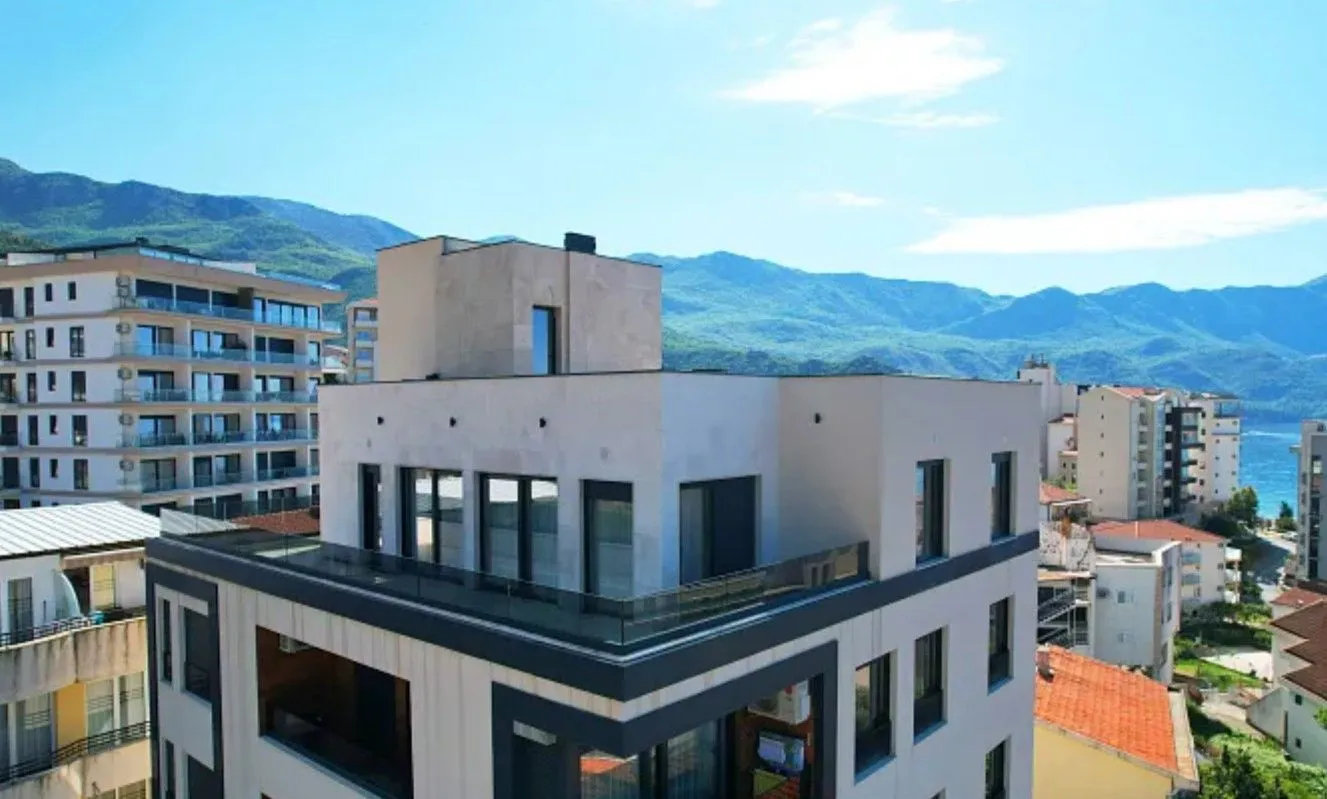 Pogled na spoljašnjost moderne stambene zgrade sa planinama u pozadini.