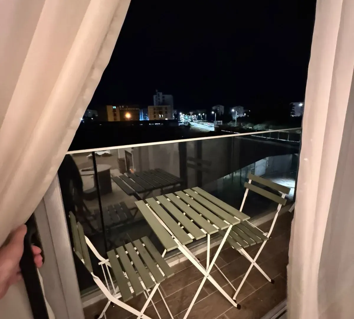 Small furnished balcony area with a table and two chairs in the evening.